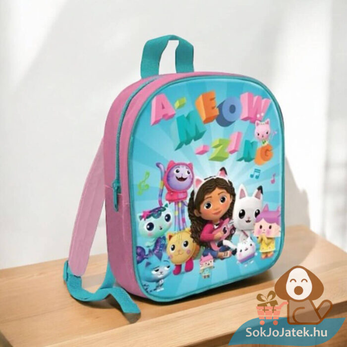 Gabi babaháza: Gabby és barátai mintás A-meow-zing feliratos rózsaszín és türkiz színű ovis, kisiskolás hátizsák az asztalon (29 cm)